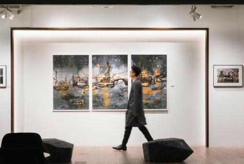 a woman walks past a painting in an art exhibit at Hotel Stage in Hong Kong