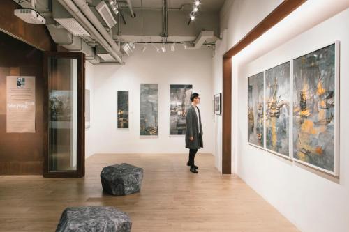 a man standing in a gallery looking at art at Hotel Stage in Hong Kong