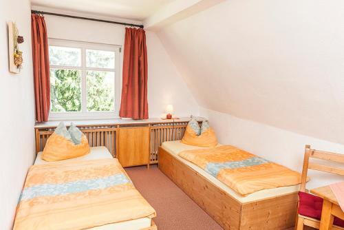 two beds in a room with a window at Pension und Gaststätte Naturbaude Eschenhof in Kurort Oberwiesenthal
