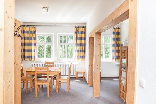a dining room with a table and chairs and windows at Pension und Gaststätte Naturbaude Eschenhof in Kurort Oberwiesenthal