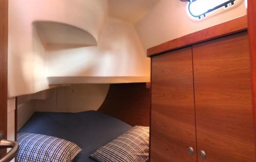 a small room with a bed under a wooden cabinet at Sailing Yacht Armida Rhodes in Rhodes Town