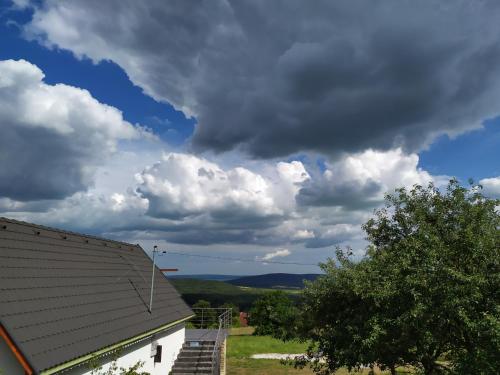 a cloudy sky with a house and a tree at Káli Vineyard Estate in Köveskál