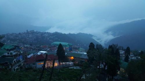 a town on a hill with a fog shrouded mountain at Hotel Taktsang Darjeeling in Darjeeling
