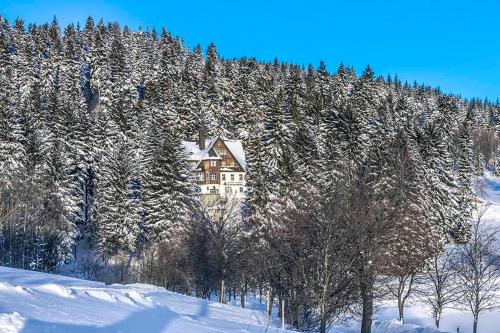 a house on the side of a snow covered mountain at Pension und Gaststätte Naturbaude Eschenhof in Kurort Oberwiesenthal