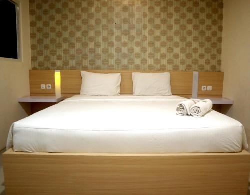 duże łóżko z białą pościelą i ręcznikami w obiekcie Jember City Hotel w mieście Jember