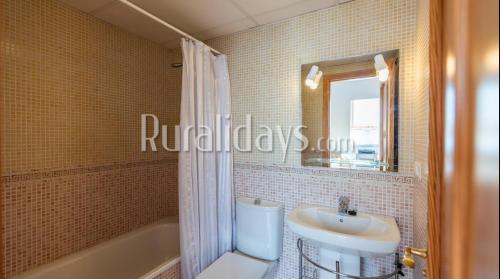 y baño con lavabo, aseo y espejo. en First line beach apartment en Algarrobo