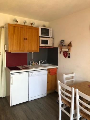 eine Küche mit weißen Geräten und einem Tisch mit Stühlen in der Unterkunft Le Bouquetin - Immeuble Le Pluton in Les Deux Alpes
