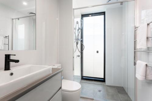 The East End Apartments by Urban Rest في أديلايد: حمام أبيض مع حوض ومرحاض