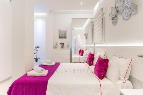 Habitación blanca con cama grande con almohadas rosas. en Apartamento Marina Beach, en Benalmádena
