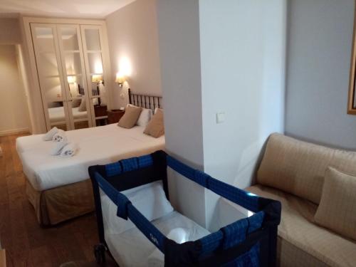 a small room with two beds and a couch at Hotel Cuéntame La Puebla in Burgos