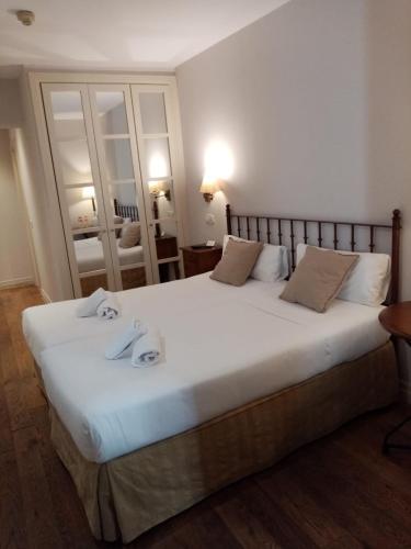 a bedroom with a large white bed with towels on it at Hotel Cuéntame La Puebla in Burgos