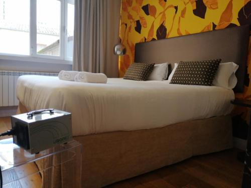 a bedroom with a large white bed with a toaster at Hotel Cuéntame La Puebla in Burgos