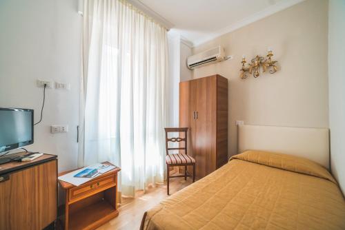 a bedroom with a bed and a tv and a chair at GH Hotel San Giusto in Rome