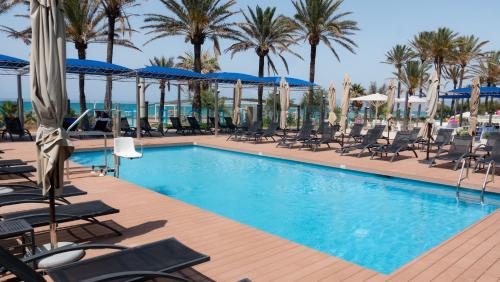 a swimming pool with chairs and palm trees at Hotel Negresco - Adults Only in Playa de Palma