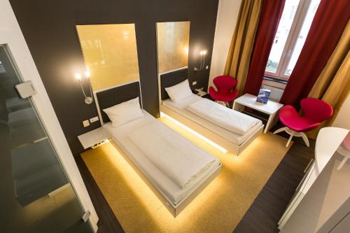 ジンスハイムにあるホテル ジンスハイムのベッド2台と赤い椅子2脚が備わる小さな客室です。