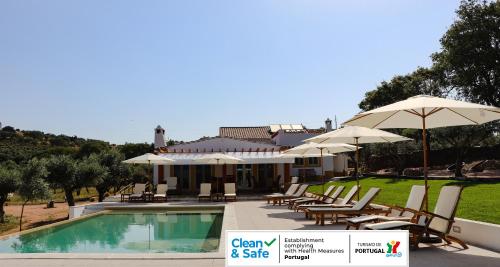 a resort with a swimming pool with chairs and umbrellas at Quinta da Soneca in Alandroal