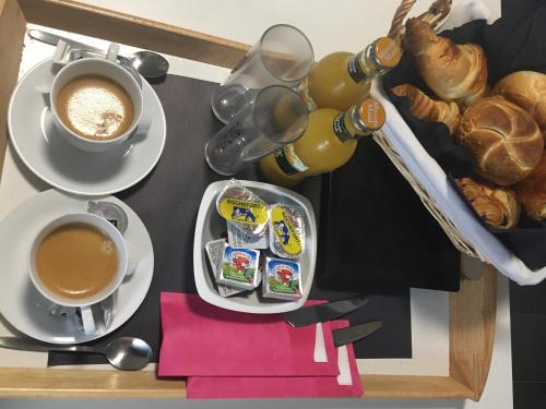 une table avec deux tasses de café et une assiette de nourriture dans l'établissement V E R O N E - Rooms & Suites - Liège - Rocourt, à Liège