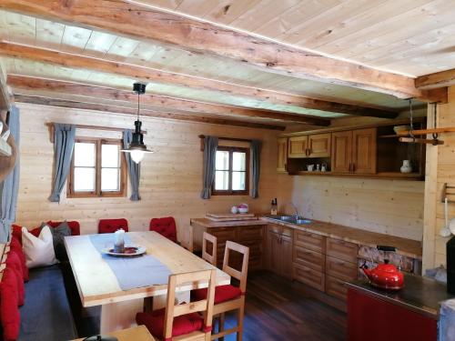 Ampferkaralm Hütte في فورستاو: مطبخ وغرفة طعام مع طاولة في كابينة