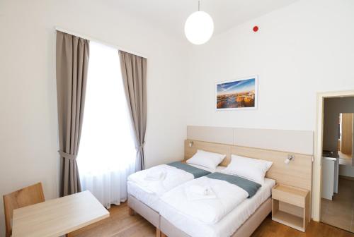 a bedroom with a white bed and a large window at Domus Peregrini Apartmanok in Győr
