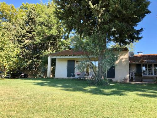 a small white house with a tree in the yard at Mas Du Pont De Laute in Le Cailar