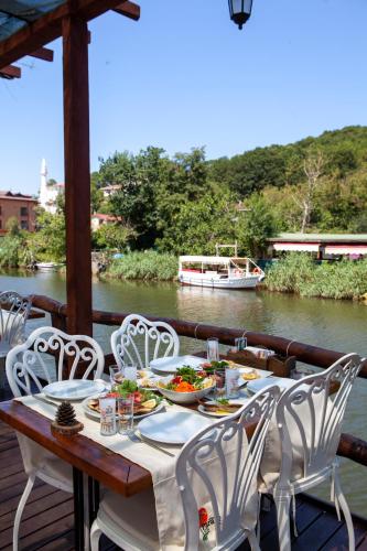 a table with white chairs and a boat on a river at Paradise Plus Ağva in Agva