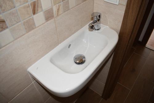 a white sink in a bathroom with aaucet at Apartmány Kubova Huť in Kubova Huť