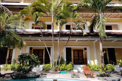 a hotel with palm trees in front of a building at Villa Puri Royan in Jimbaran