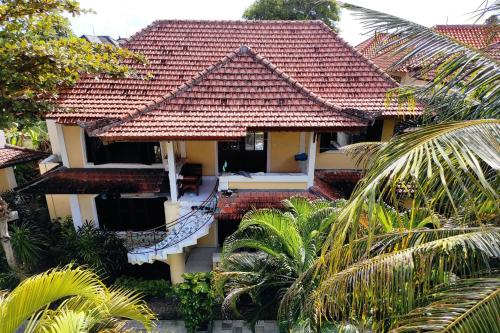 a house with a red roof and some palm trees at Villa Puri Royan in Jimbaran