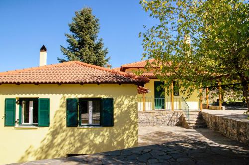 a yellow house with green shutters on it at Dual house in Methydrio in Vytina