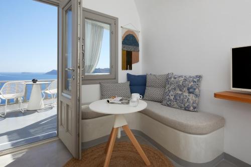 a room with a table and a chair and a balcony at Filotera Suites in Oia