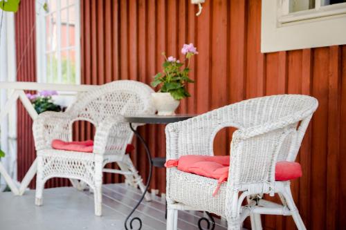 two white wicker chairs with red cushions on a porch at Villa Tammikko in Tuusula