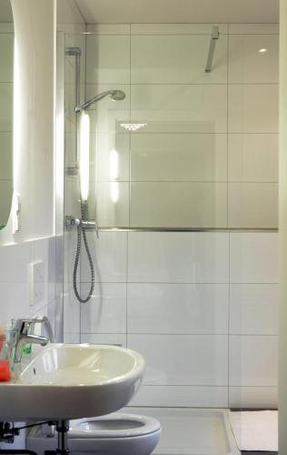 a bathroom with a sink and a glass shower at Restaurant Trocadero in Hannover
