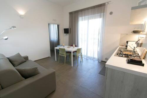 a kitchen and a living room with a couch and a table at Via Del Faro Apartments in Torre Canne