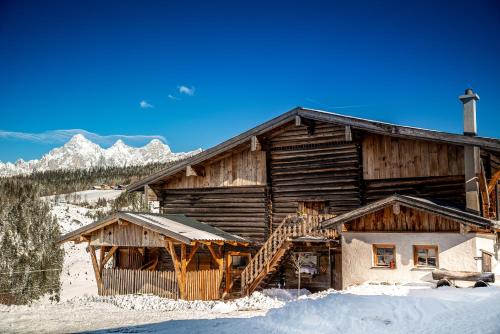 a log cabin in the snow with mountains in the background at Erblehenhof in Forstau