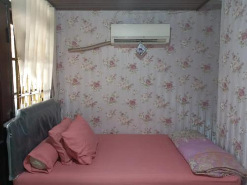 a bedroom with a bed with pink pillows and a window at Mayestik Guest House Syariah in Jakarta