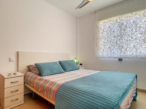 sypialnia z łóżkiem z niebieską kołdrą i oknem w obiekcie Albatros Playa 3 - 4908 w mieście Mar de Cristal
