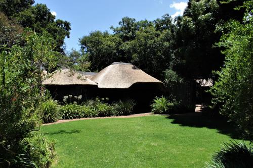 a thatch roofed house with a green lawn at Ikamu's lodge in Germiston