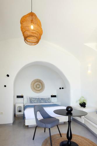 a bedroom with a bed and a table and a chair at Filotera Suites in Oia