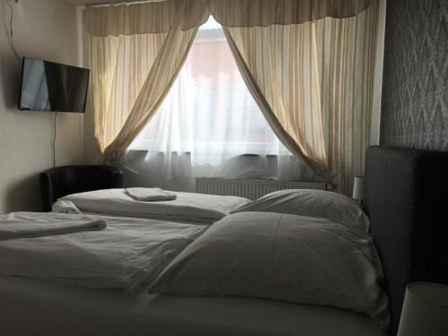 two beds in a hotel room with a window at Pension Alis Augsburg in Augsburg
