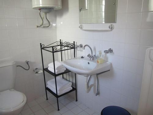 a white bathroom with a sink and a toilet at Arsinoe - Cosy guesthouse- in Methana