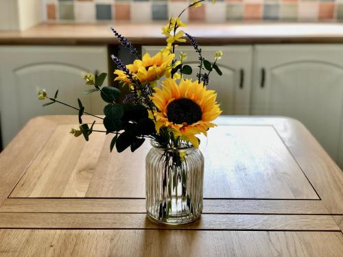 a vase filled with yellow flowers sitting on a table at Bodarfor in Trearddur