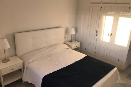 a bedroom with a white bed and two night stands at Precioso apartamento muy cerca de la playa in Chiclana de la Frontera