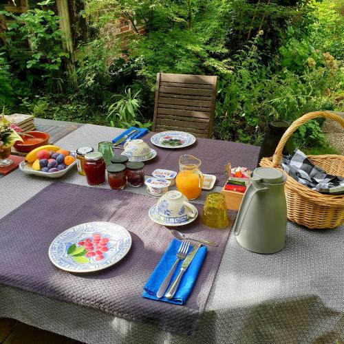 une table avec des assiettes de nourriture et un panier de fruits dans l'établissement La petite maison du jardin d'Apollon, à Dourdan