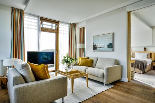 a living room filled with furniture and a tv at BUDERSAND Hotel - Golf & Spa - Sylt in Hörnum