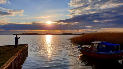 a man taking a picture of a boat on a lake at Strandburg, das smarte Penthouse in ÜckeRitz mit PKW Stellplatz! in Ueckeritz