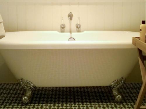 a bath tub with a sink in a bathroom at The Green Man Boutique Hotel in Takeley