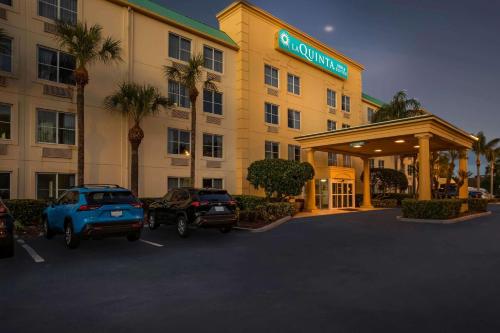 a hotel with two cars parked in a parking lot at La Quinta by Wyndham Melbourne Viera in Melbourne