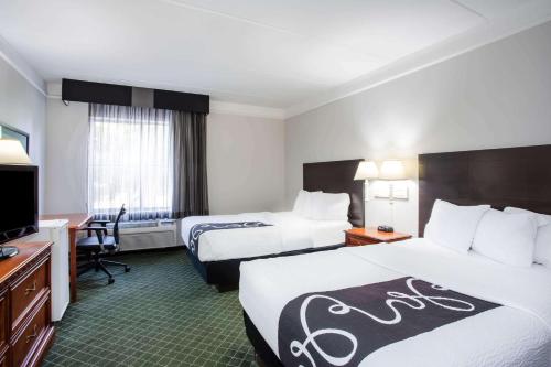 a hotel room with two beds and a television at La Quinta by Wyndham Melbourne Viera in Melbourne