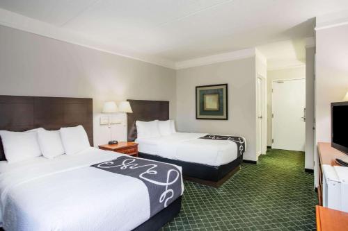 a hotel room with two beds and a flat screen tv at La Quinta by Wyndham Melbourne Viera in Melbourne
