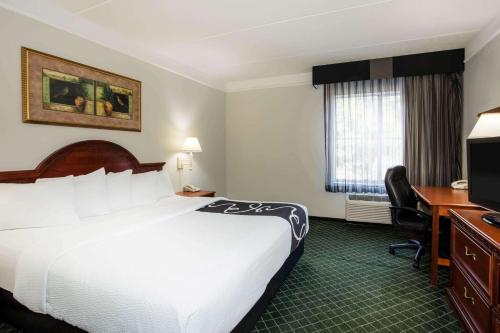 a hotel room with a bed and a desk and a television at La Quinta by Wyndham Melbourne Viera in Melbourne